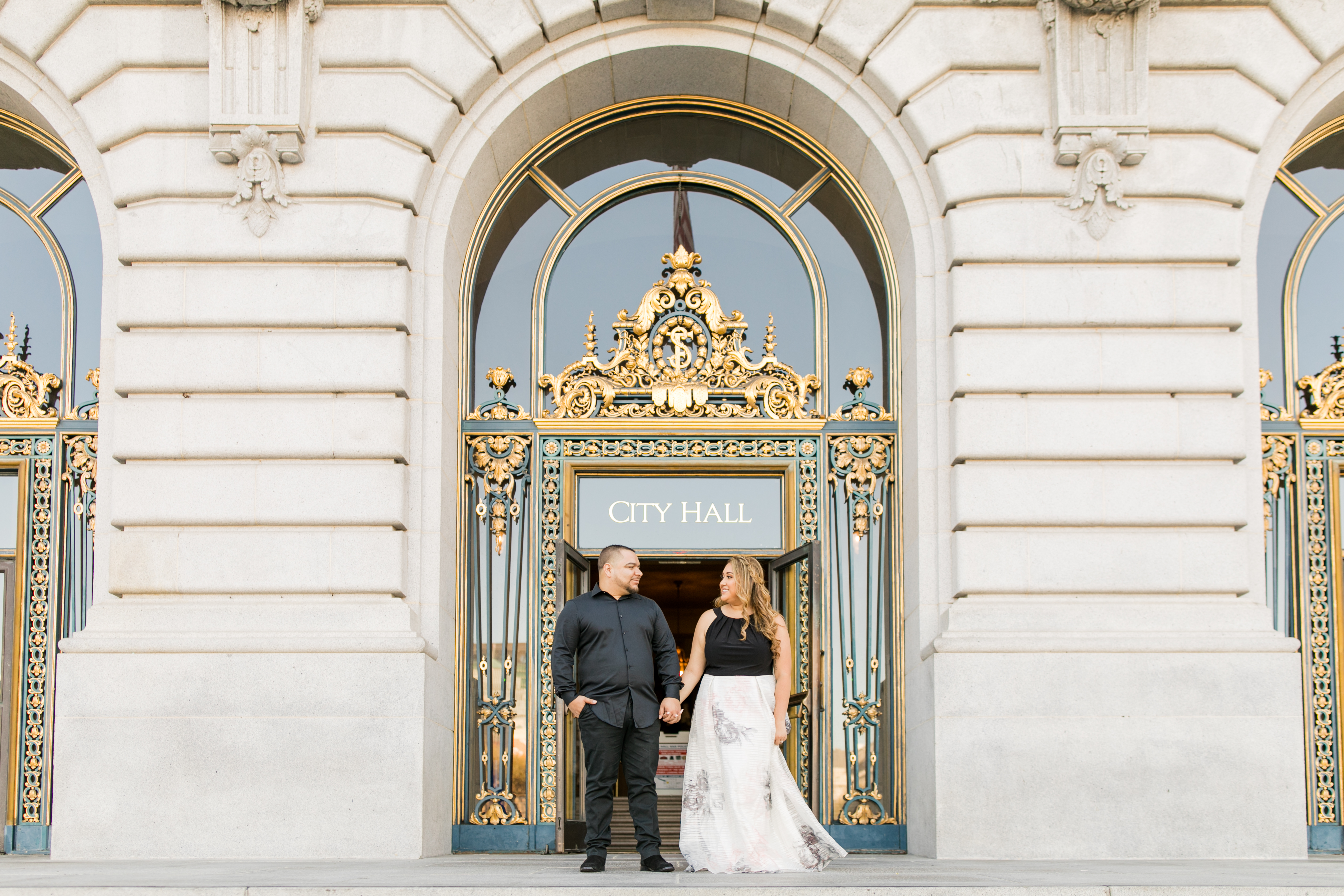 engagement session couple standing outside san francisco city hall holding hands for engagement pictures