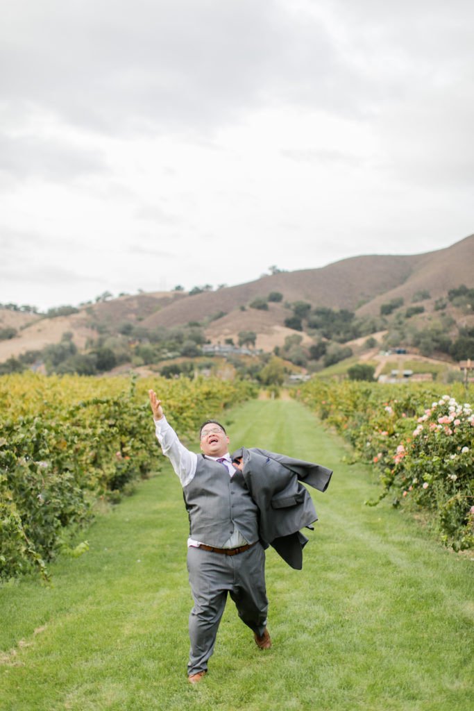 Groom running and laughing in vineyard - Kirigin Cellars - Angela Sue Photography