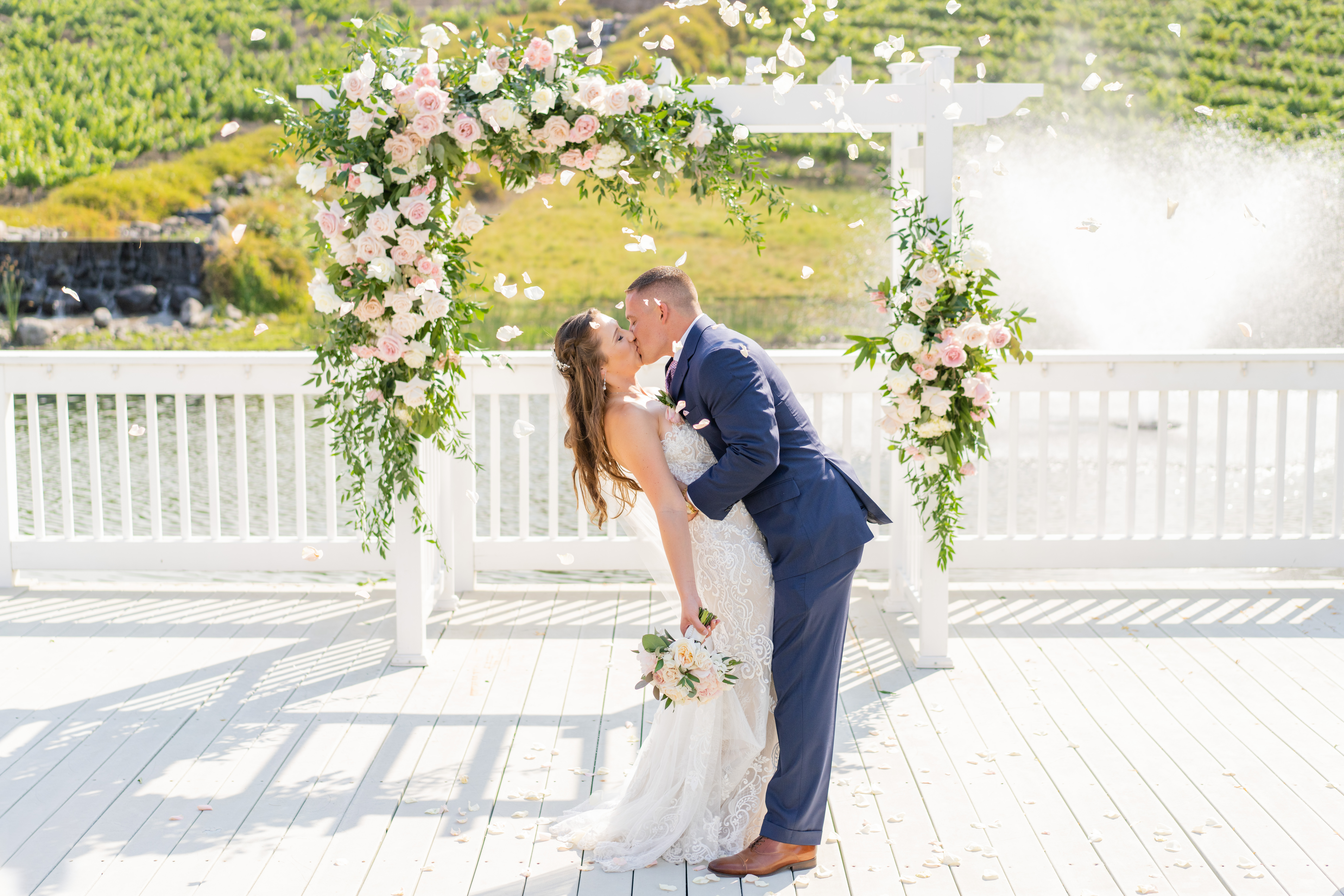 newlyweds kiss under wedding arch