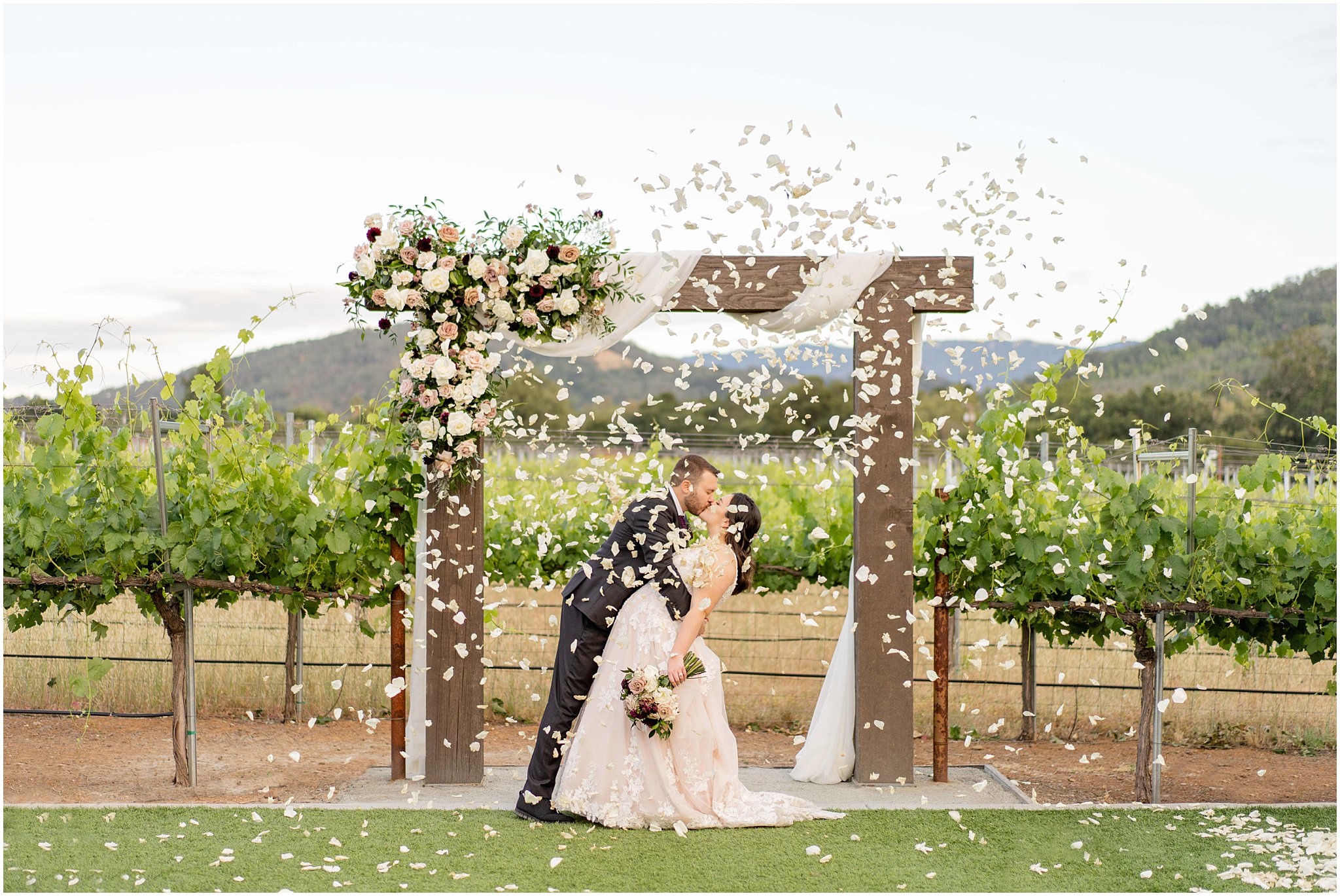 newlyweds kissing under falling rose petals