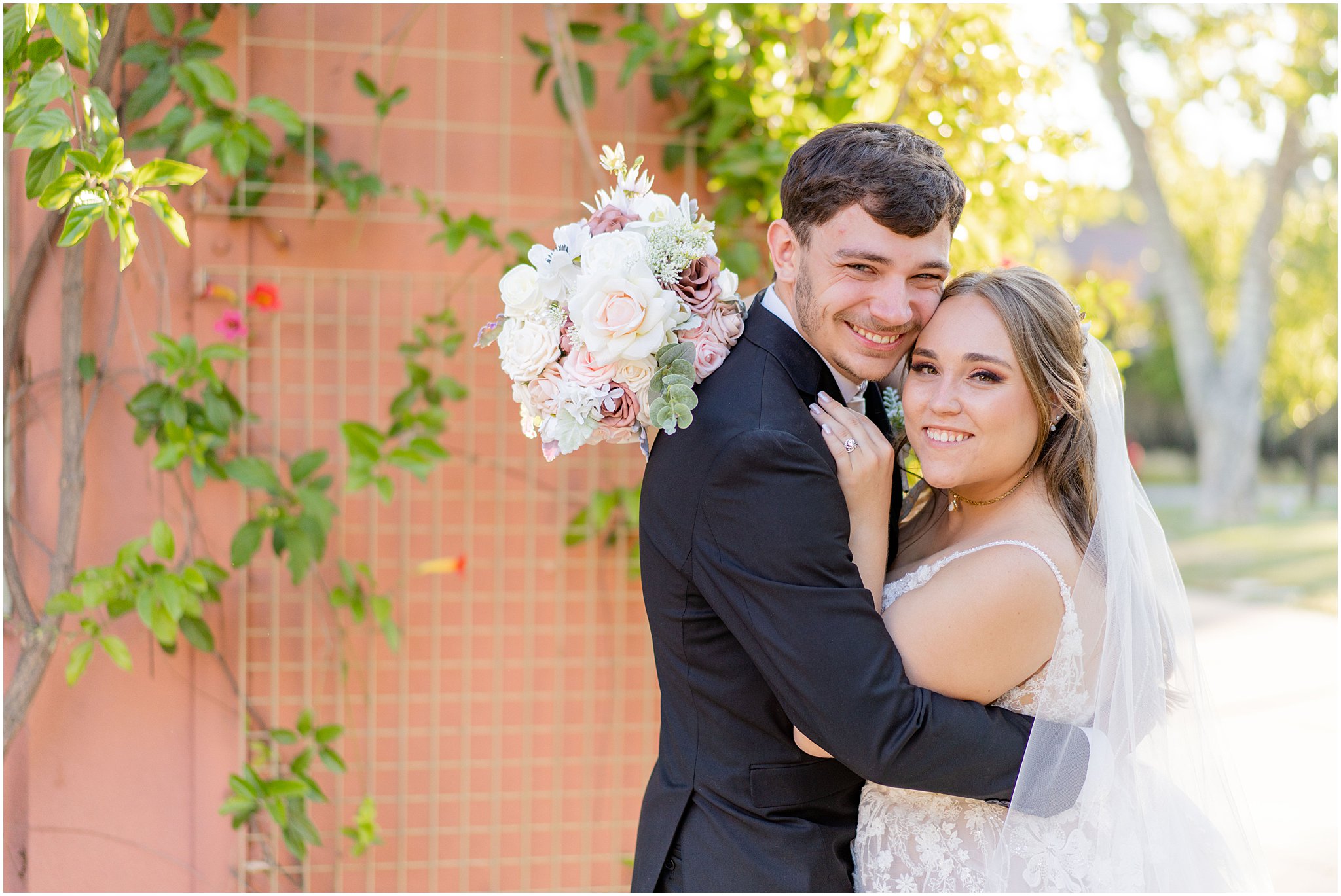 newlyweds embrace smiling at the camera
